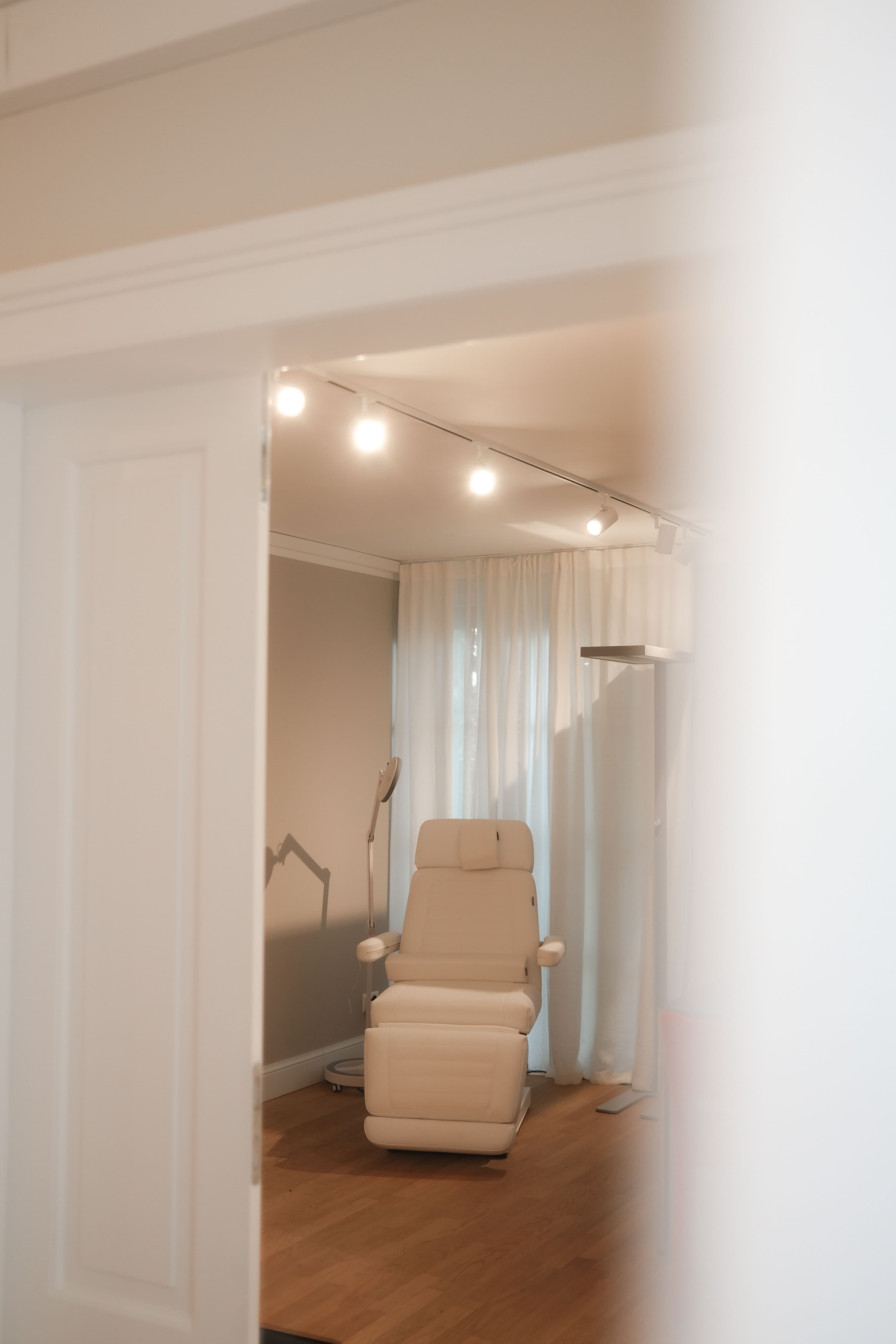 Behandlungsraum der Metropolitan Clinic Zürich mit weißer Liege, elegantes Klinikinterieur mit Naturholz