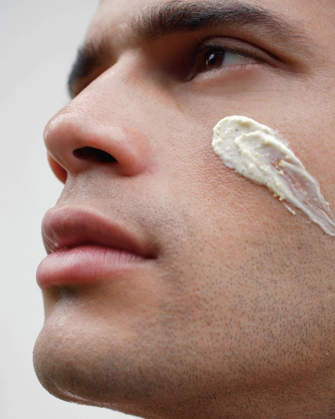 Mann mit weisser Pflegecreme auf der Wange, männliche Gesichtspflege in der Klinik