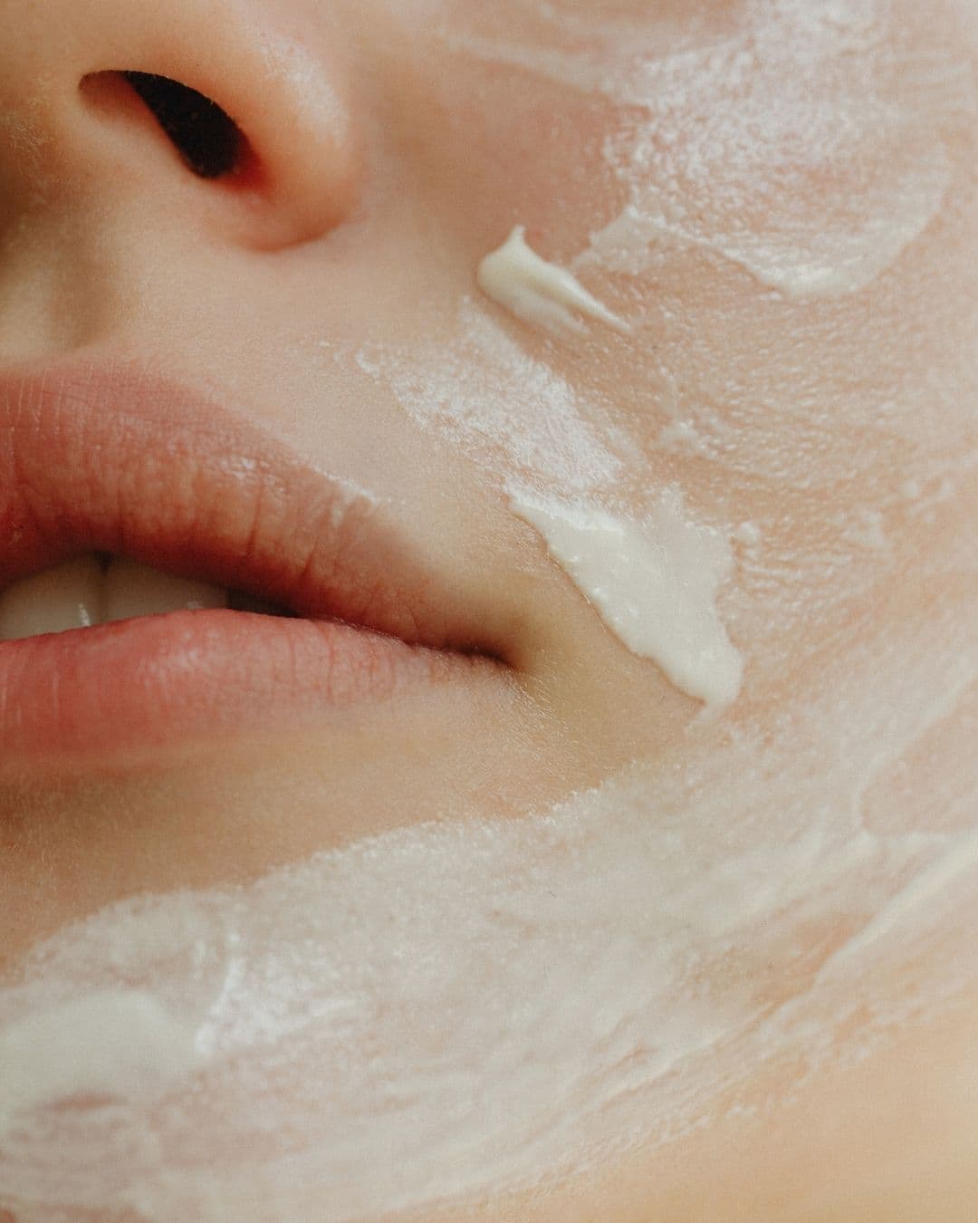 Nahaufnahme Mundpartie mit aufgetragener weisser Creme, kosmetische Gesichtsbehandlung