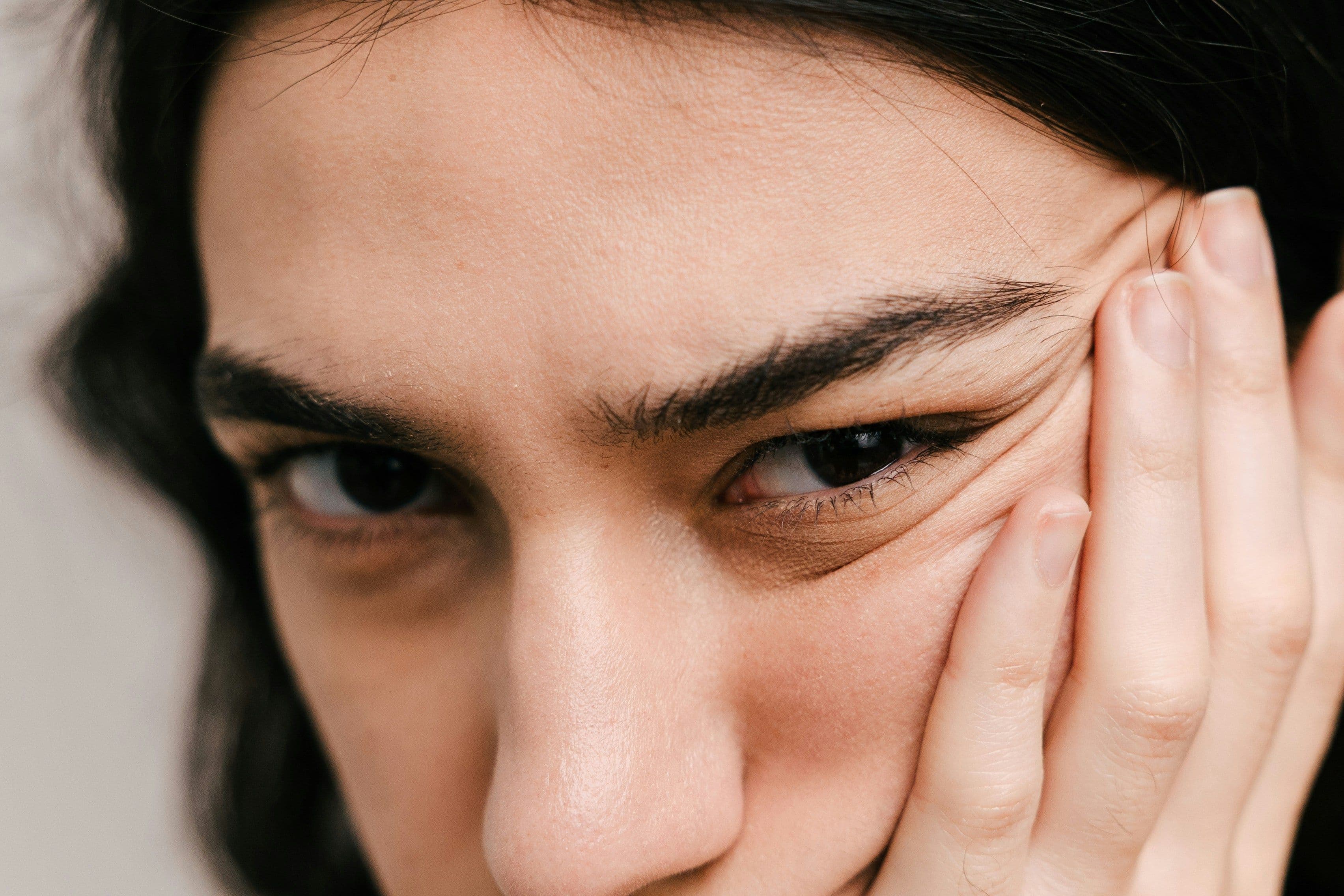 Frau hält Hand ans Gesicht, intensive Nahaufnahme der Augenpartie